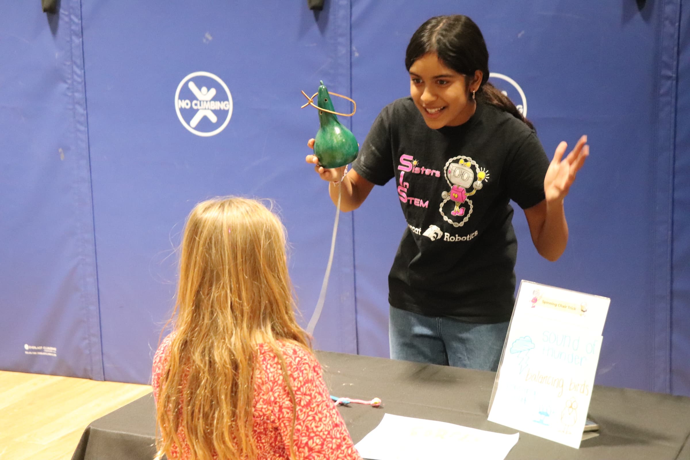 Girl being taught by excited SiS volunteer on how a simple construction can make the sound of thunder