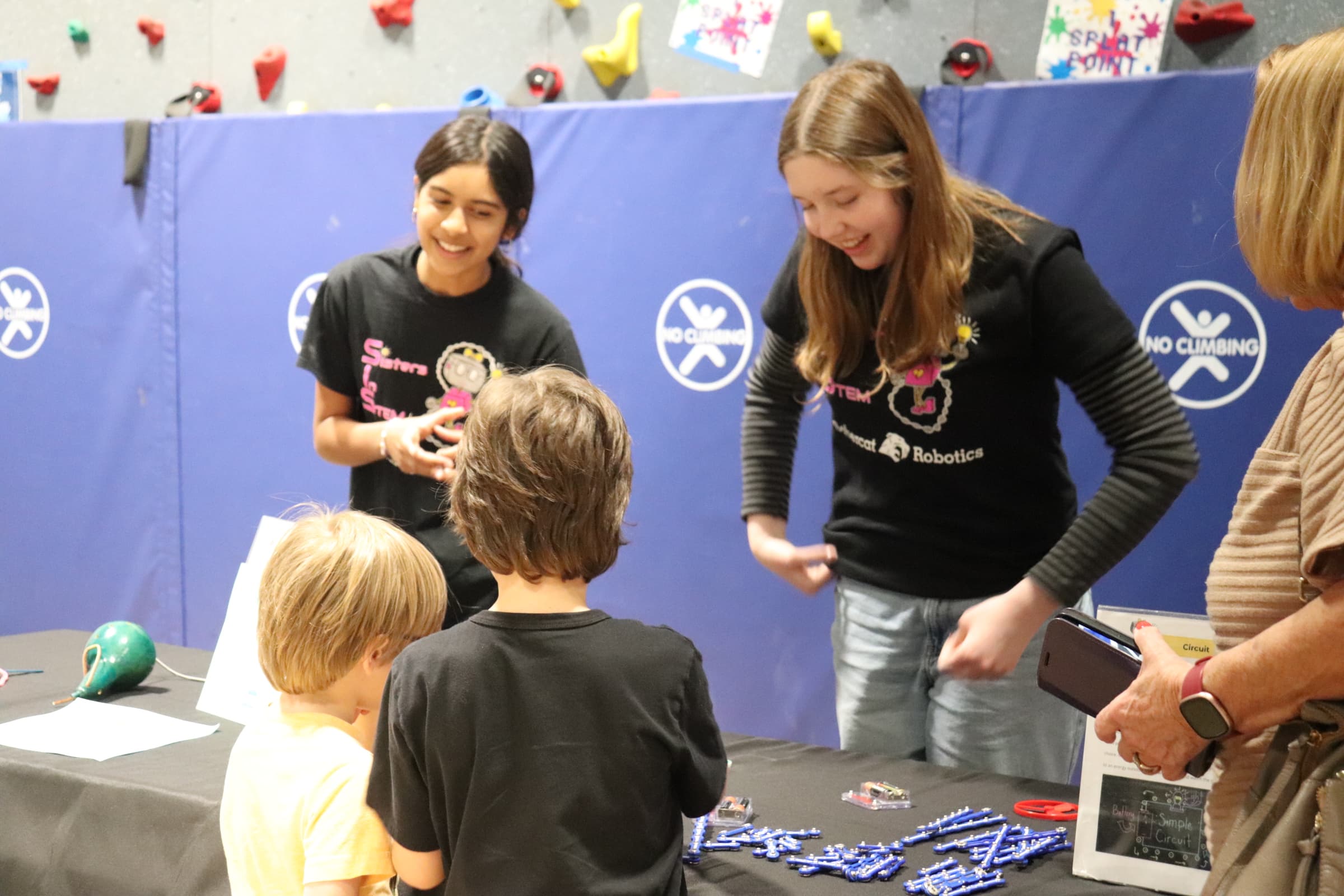 Two SiS volunteers teaching 2 young boys a STEM experiment