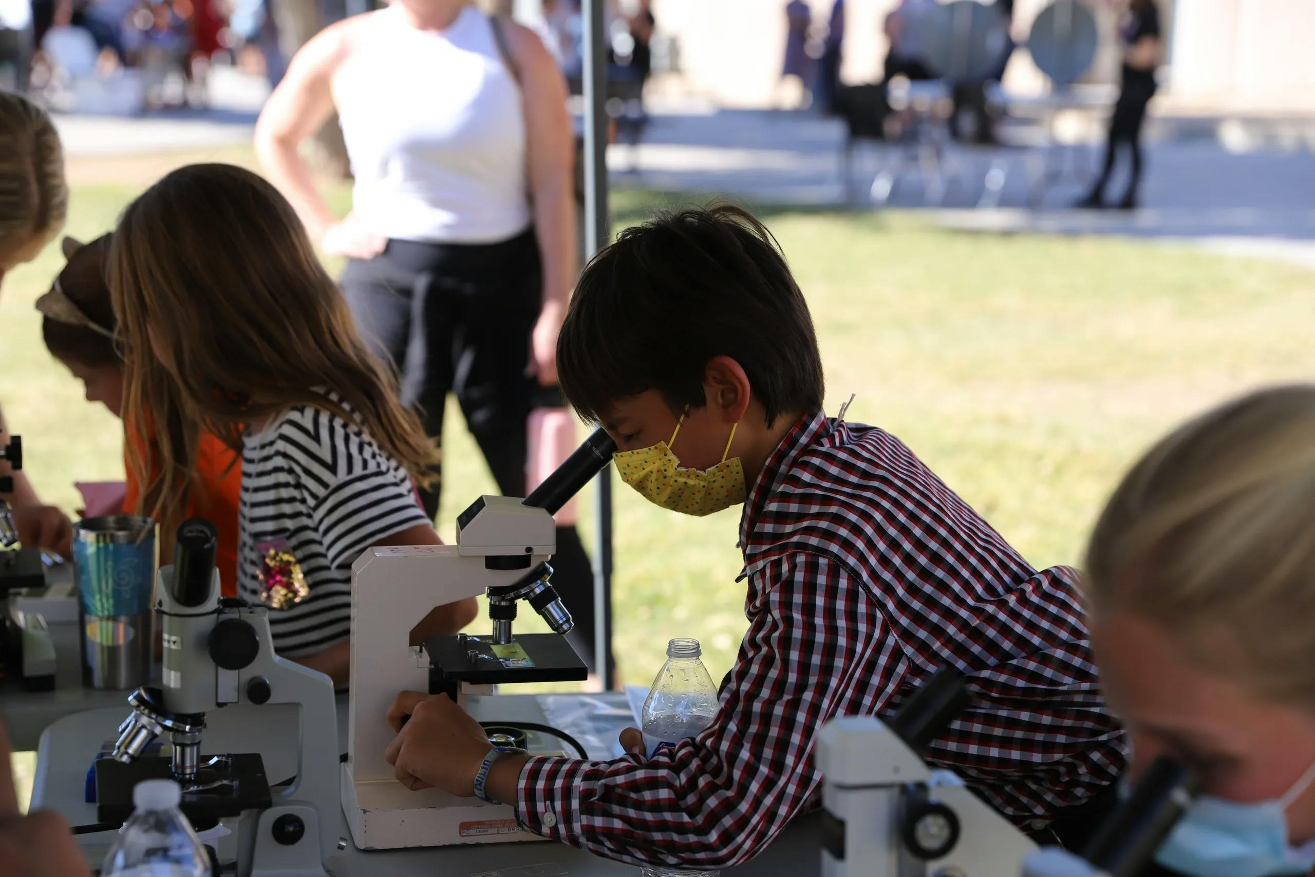 Boy looking through microscope to learn about biology.